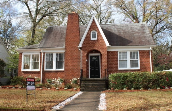 old brick home with a for sale sign awaiting inspection